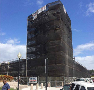 A building wrapped in black debris netting 